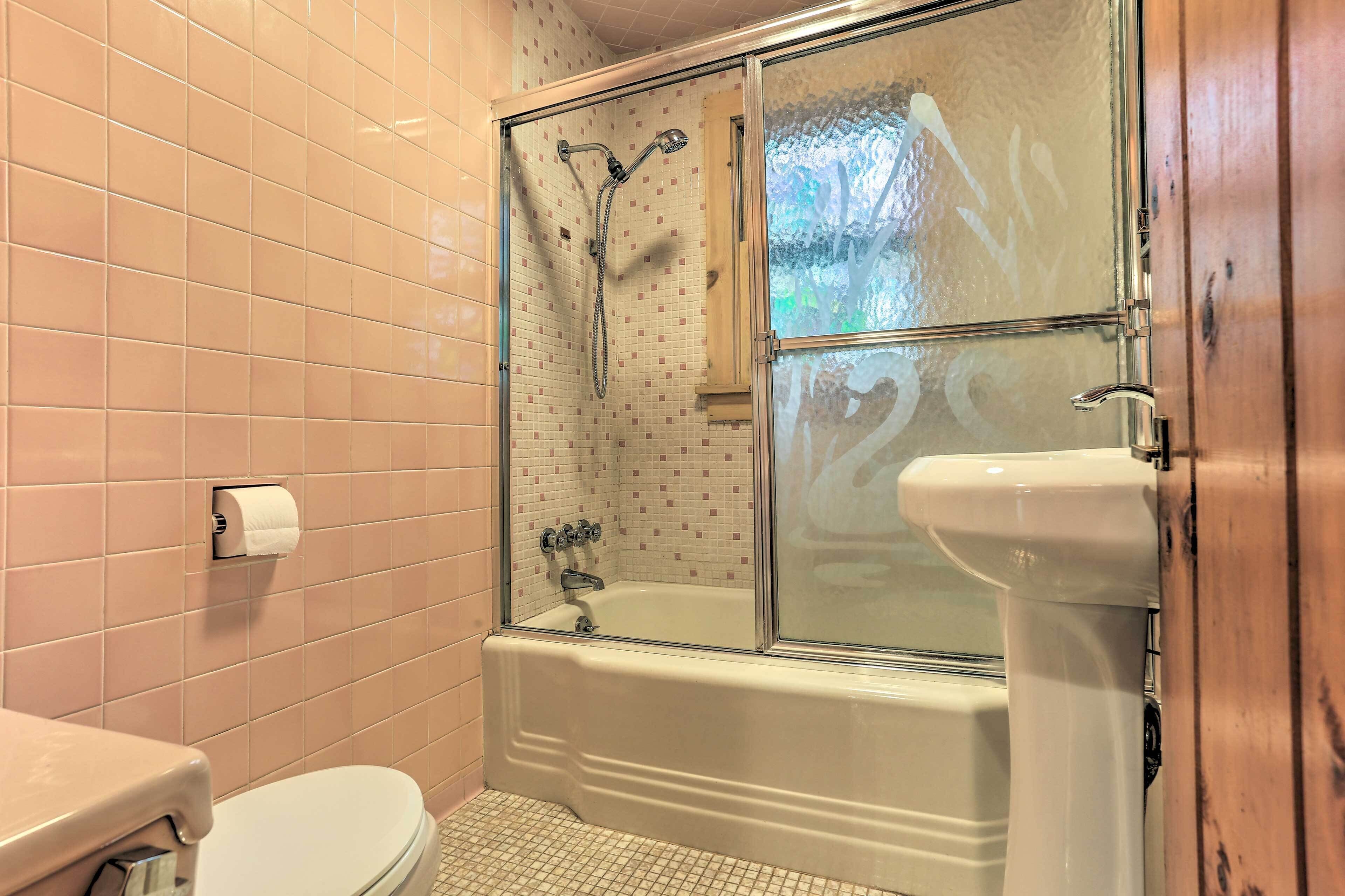 Un baño con ducha envuelta en vidrio, bañera blanca y un inodoro.