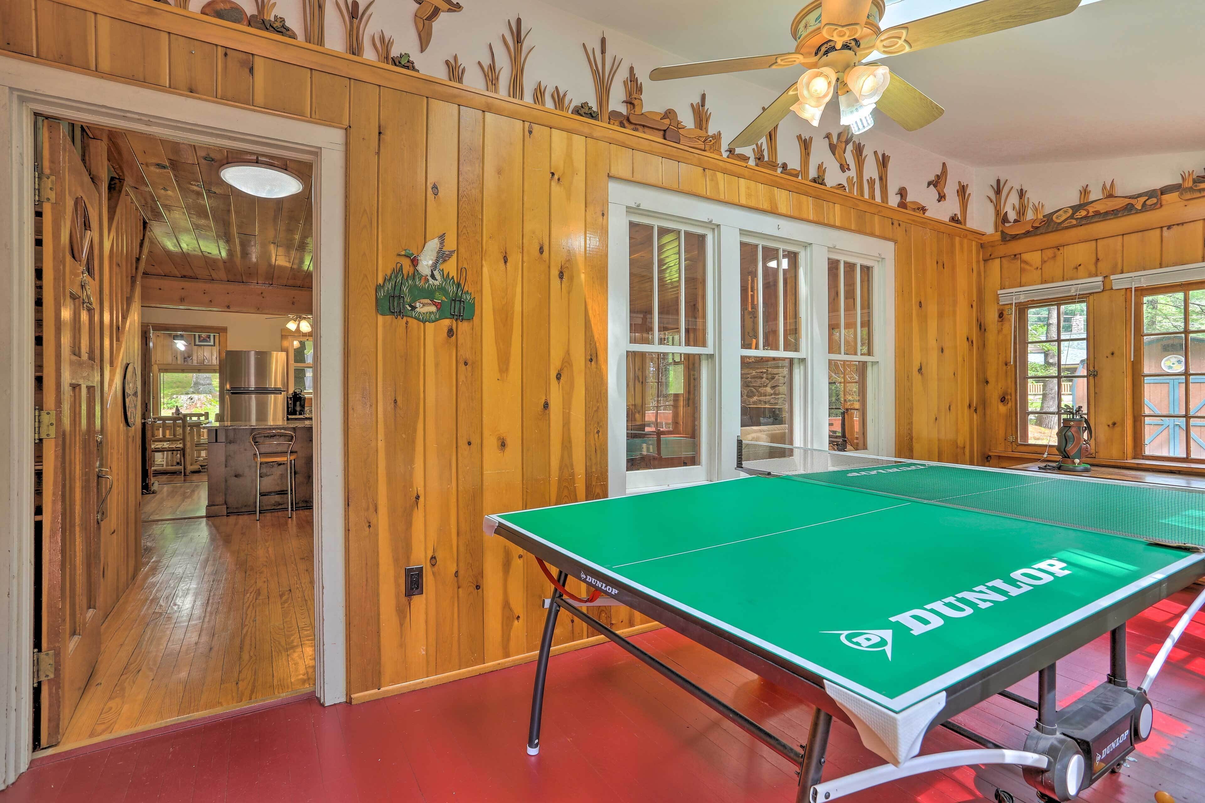 A ping pong table with a green surface and 'DUNLOP' branding, set in a room with wooden walls and a red floor.