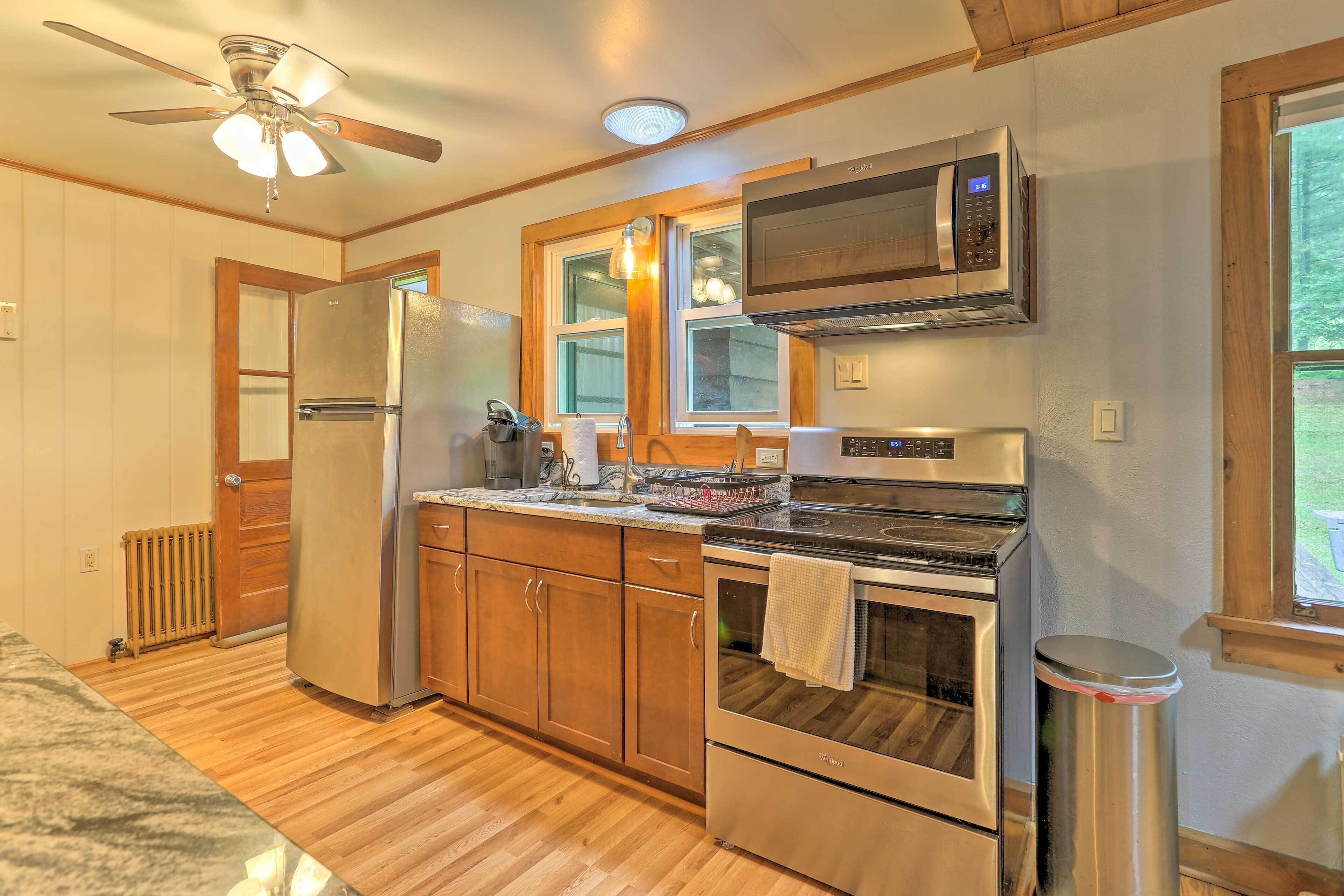 A kitchen with wooden cabinets, a stainless steel refrigerator, a microwave, and an oven.