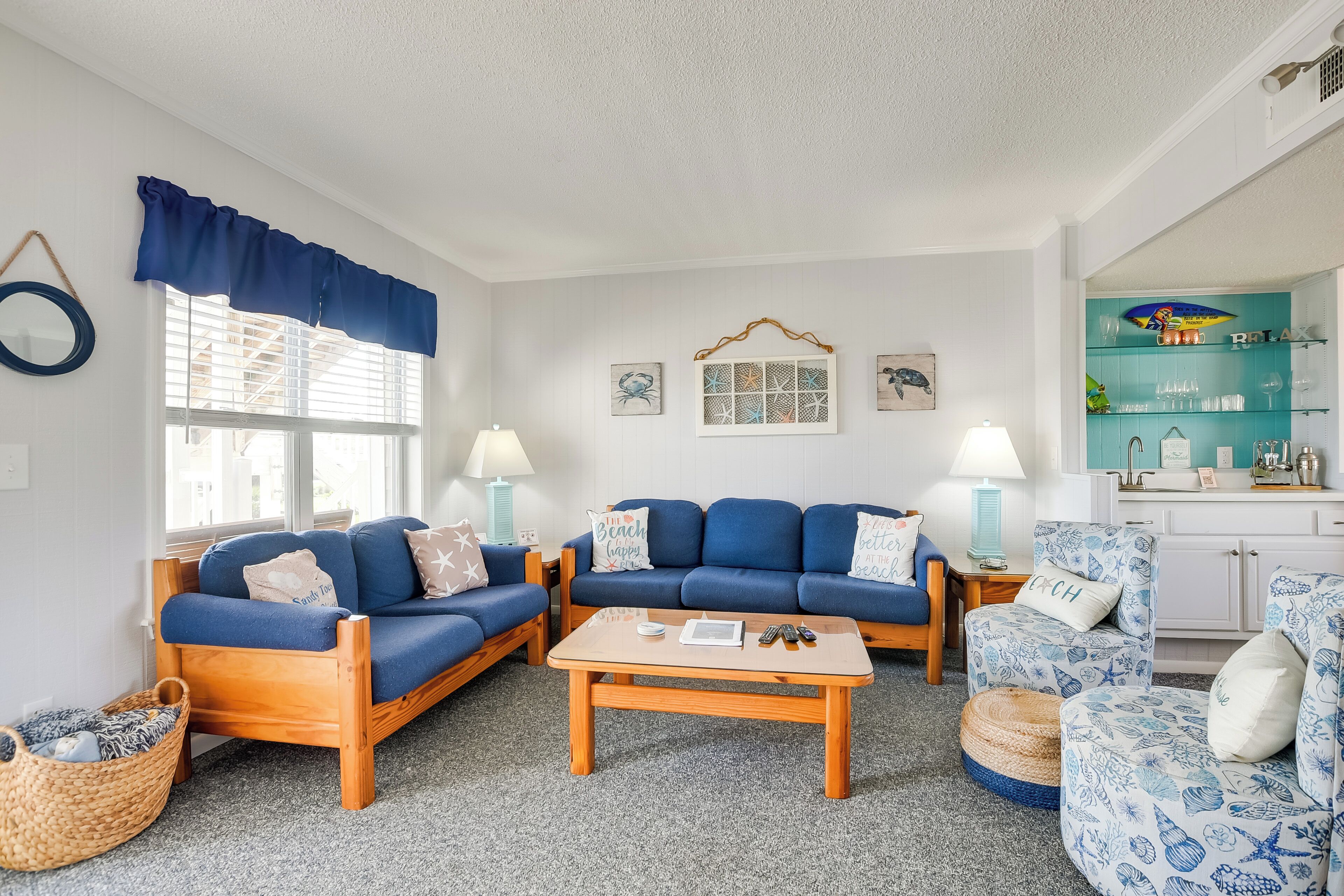 A living room with two blue sofas, a wooden coffee table, and a teal accent wall.
