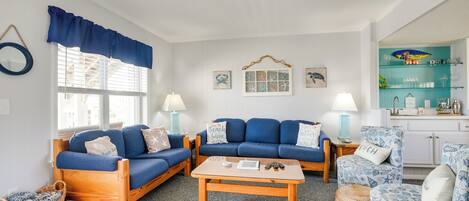 A living room with two blue sofas, a wooden coffee table, and a teal accent wall.