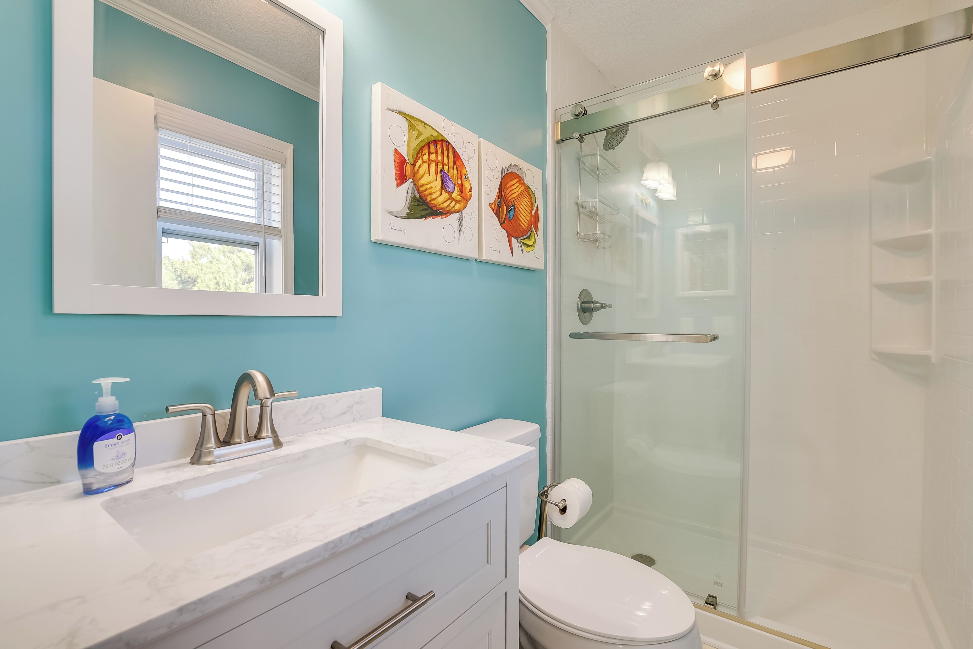Un baño con un lavabo blanco, un inodoro y una ducha con mampara de vidrio.