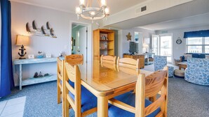 Un comedor con una mesa y sillas de madera, una araña y una estantería.