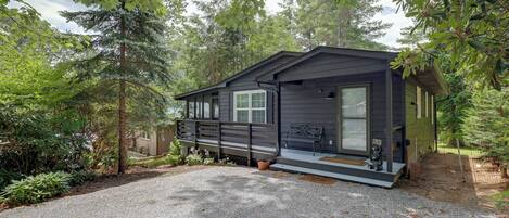 A cabin with a gravel driveway, surrounded by trees.