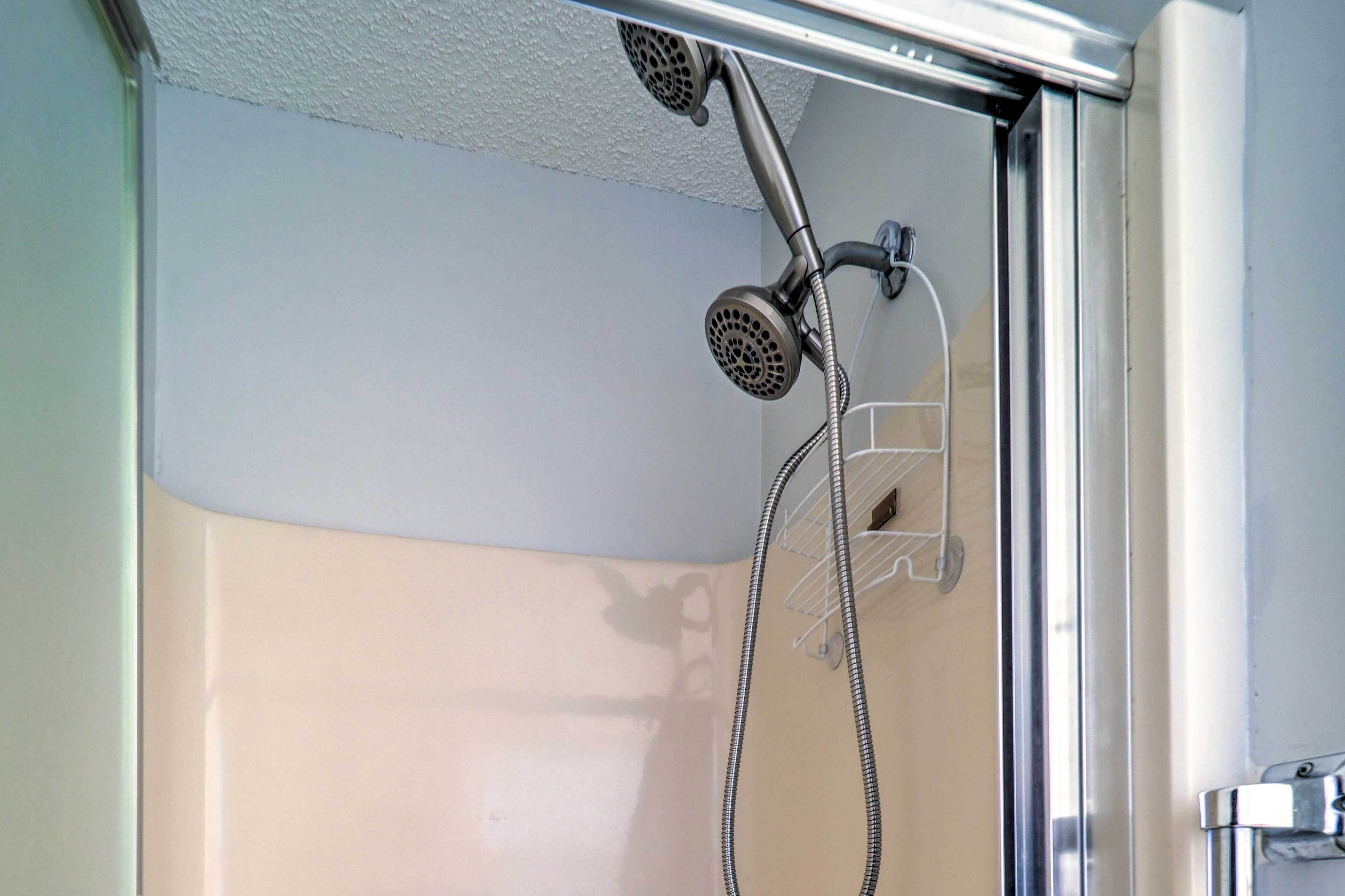 A shower with a handheld showerhead and a hose.