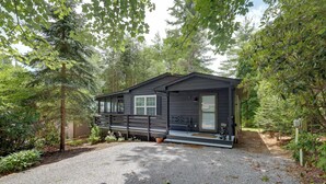 A cabin with a gravel driveway, surrounded by trees. - In Golf Community w/ Pool Access: Newland Cabin (Newland)