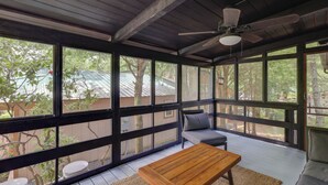 A covered porch with a wooden table and seating, large windows, and a ceiling fan. - In Golf Community w/ Pool Access: Newland Cabin (Newland)