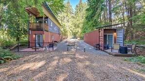 A cabin with a deck, surrounded by dense forest. - Steps to Foothills Trail: Unique Carbonado Studio (Carbonado)