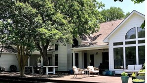 A house with a covered patio, outdoor seating, and a large window. - Lap Pool, Infrared Sauna & 1+ Acre in South Austin (Austin)