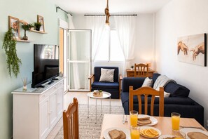 A compact living space with a kitchenette, a dining area with breakfast, a sofa, and a TV. - Apartamento El Calón Playa - Lateral Luz (El Calón)