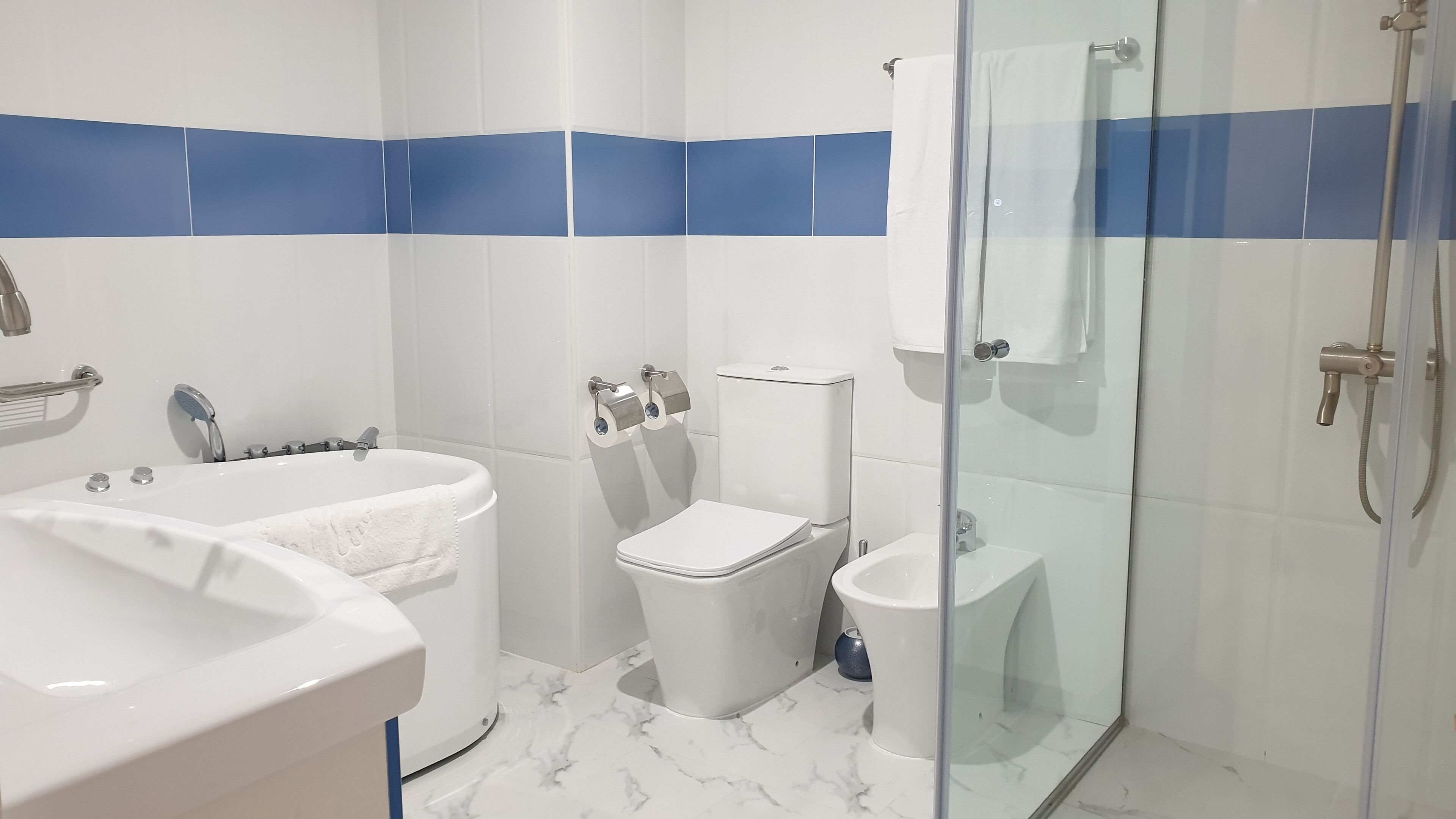 A modern bathroom with a bathtub, toilet, and shower.