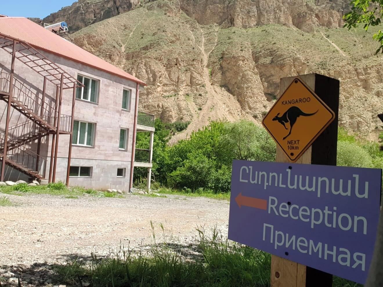 A building with a red roof and a sign indicating a kangaroo crossing 10 km ahead.