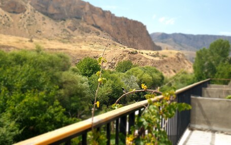 A balcony with a view of a mountainous landscape, a railing, and some greenery.