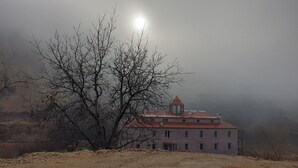 A building with a red roof and a tower, surrounded by leafless trees and a foggy atmosphere. - Areni Lodge (Areni)