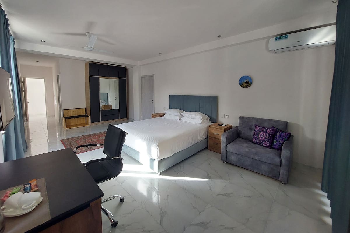 Una camera d'albergo con un letto, una scrivania, una sedia, un armadio e un condizionatore.