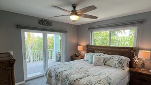 Una camera da letto con un letto grande, un ventilatore a soffitto, un comodino con una lampada e un comò.