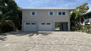 Una casa a due piani con garage, vialetto in pietra e prato curato.