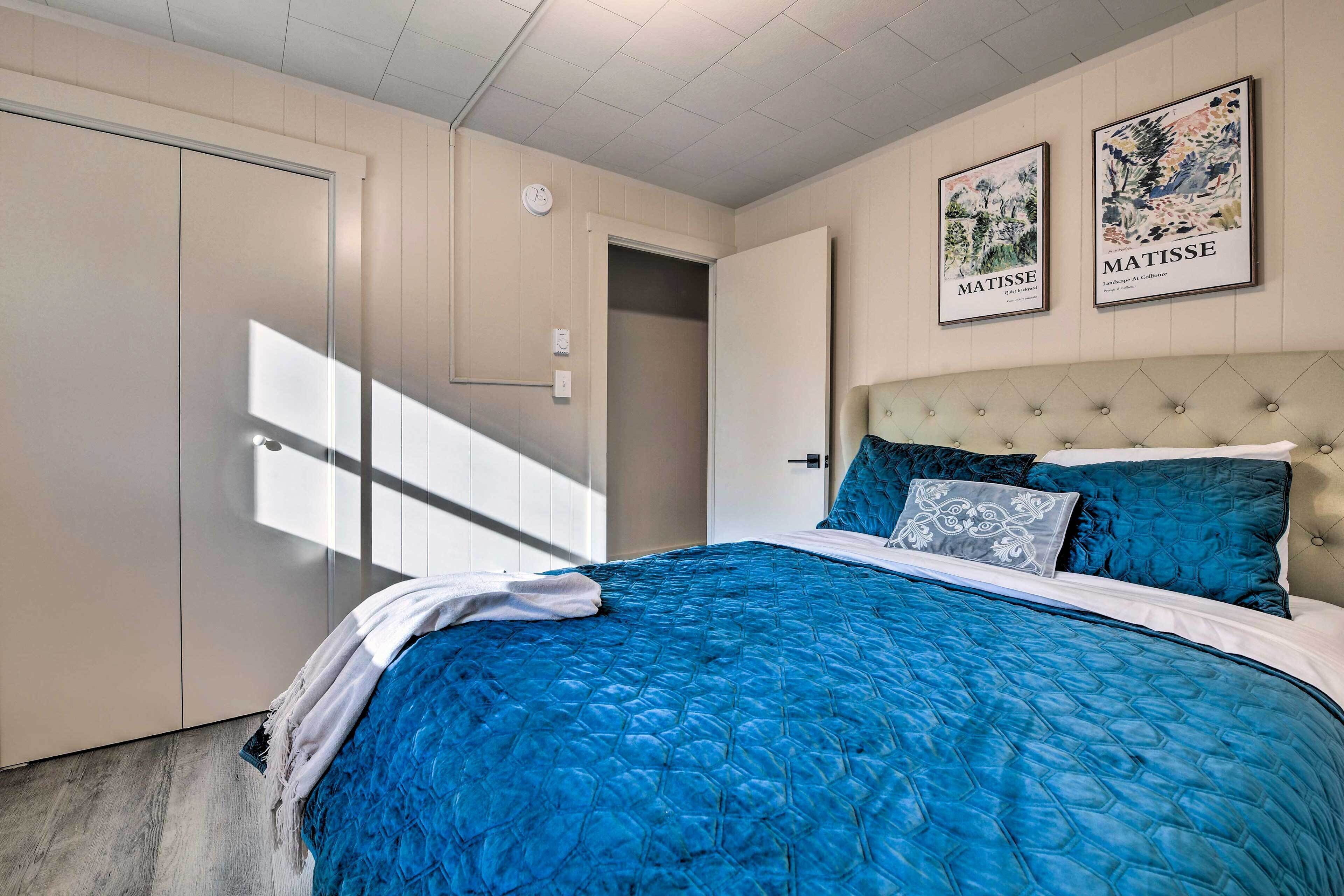 Ein Schlafzimmer mit einem großen Bett, einem Kopfteil, zwei Wandbildern und einer Tür.