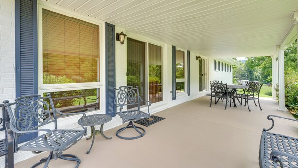 A covered porch with outdoor furniture, including chairs and a table. - Near Hiking: Home w/ Trout Stream in Bakersville! (Bakersville)