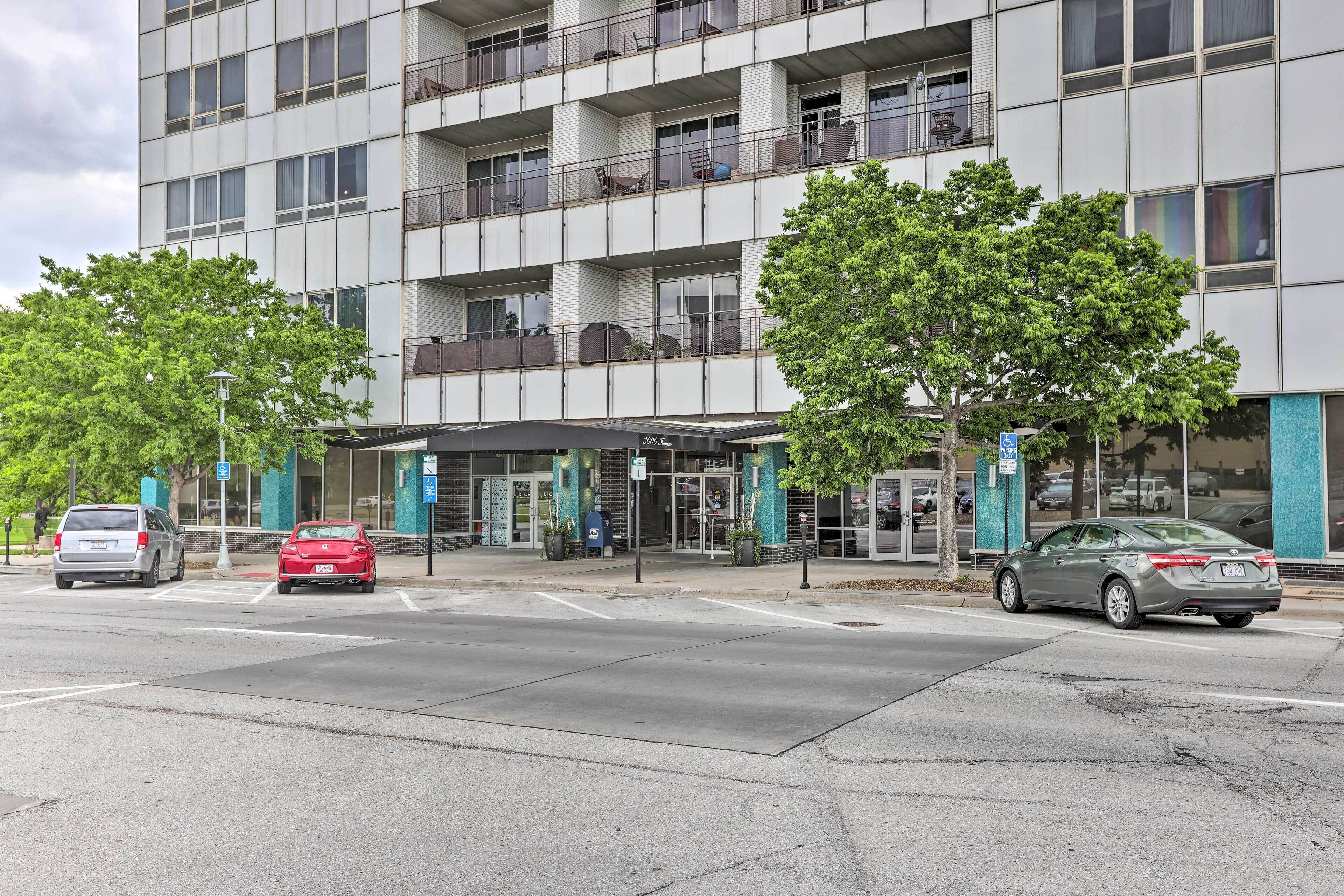 A multi-story hotel with a modern facade, outdoor seating, and a parking area.