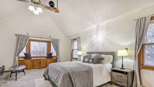 A bedroom with a large bed, bedside tables with lamps, a window seat, and a ceiling fan. - 5-acre Vacation Home w/ Woods & Hiking Ground (Pickerington)