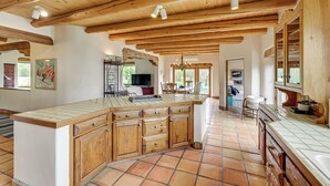 Une cuisine spacieuse avec des meubles en bois, un grand îlot central et un sol carrelé.