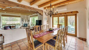 Un vaste espace dédié à la salle à manger, avec une table et des chaises en bois, un lustre et de grandes fenêtres donnant sur l’extérieur.