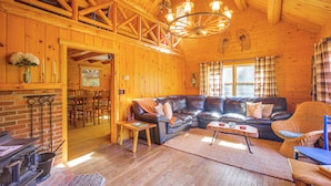 A cozy cabin interior with a wooden interior, a fireplace, a sofa, and a dining area. - Andover Cabin Retreat w/ Hot Tub & Fireplace! (Chester)