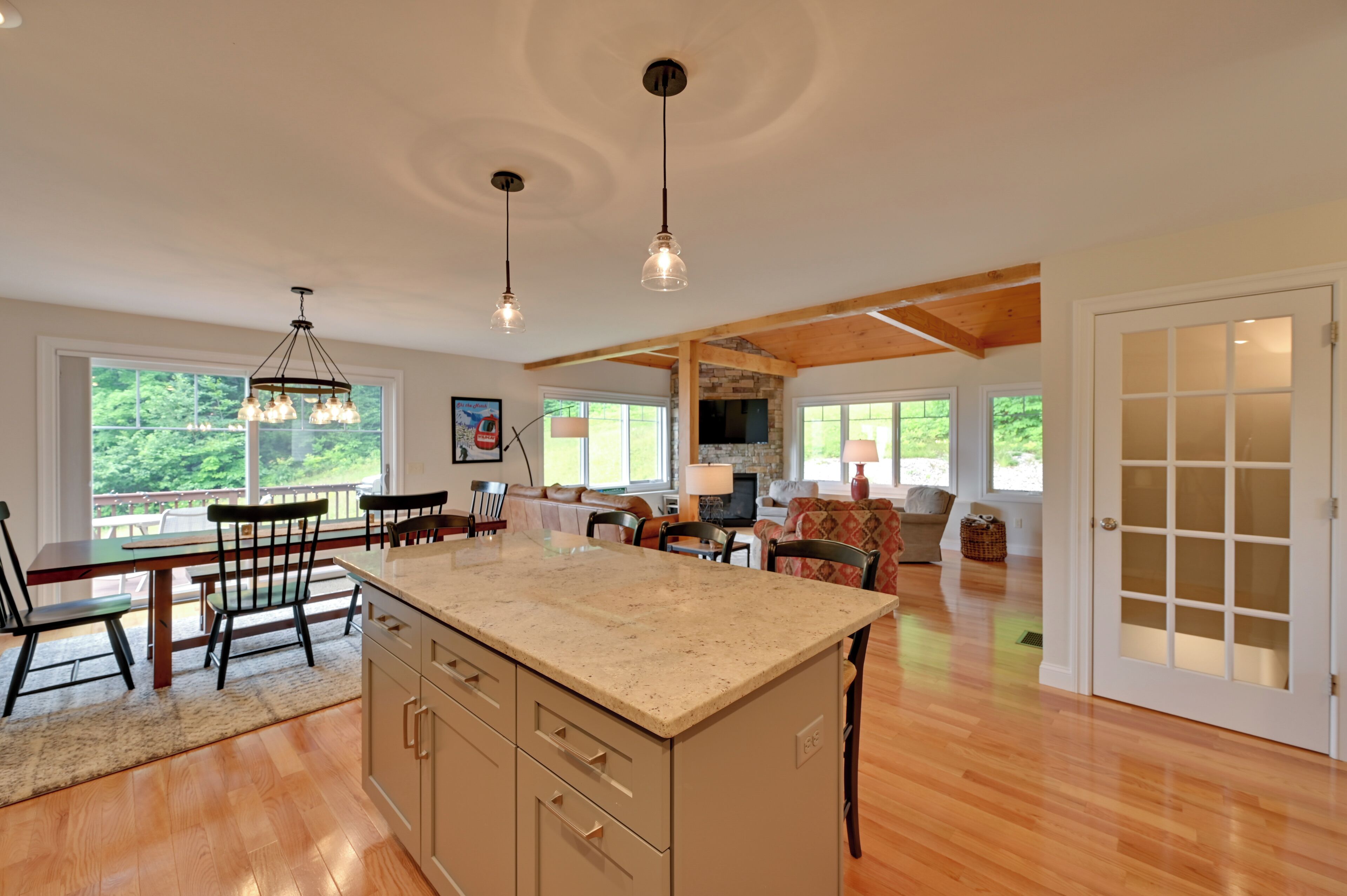 A spacious kitchen with a large island, wooden beams, and pendant lighting.