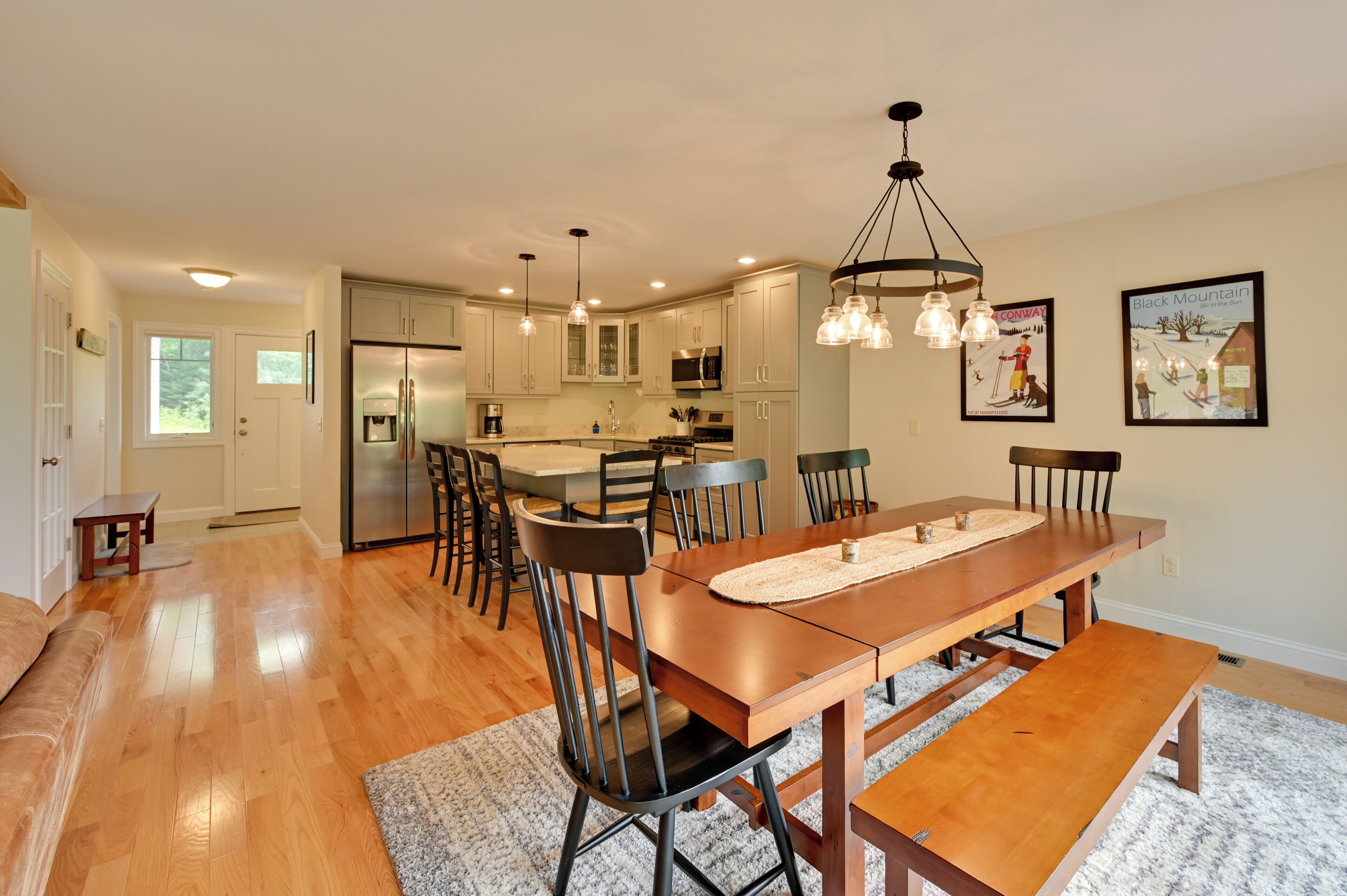 A spacious kitchen with modern appliances, a dining area with a wooden table and chairs, and a cozy seating area with a bench.