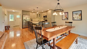 A spacious kitchen with modern appliances, a dining area with a wooden table and chairs, and a cozy seating area with a bench. - Ski In & Out! Black Mountain Resort Townhome (Jackson)