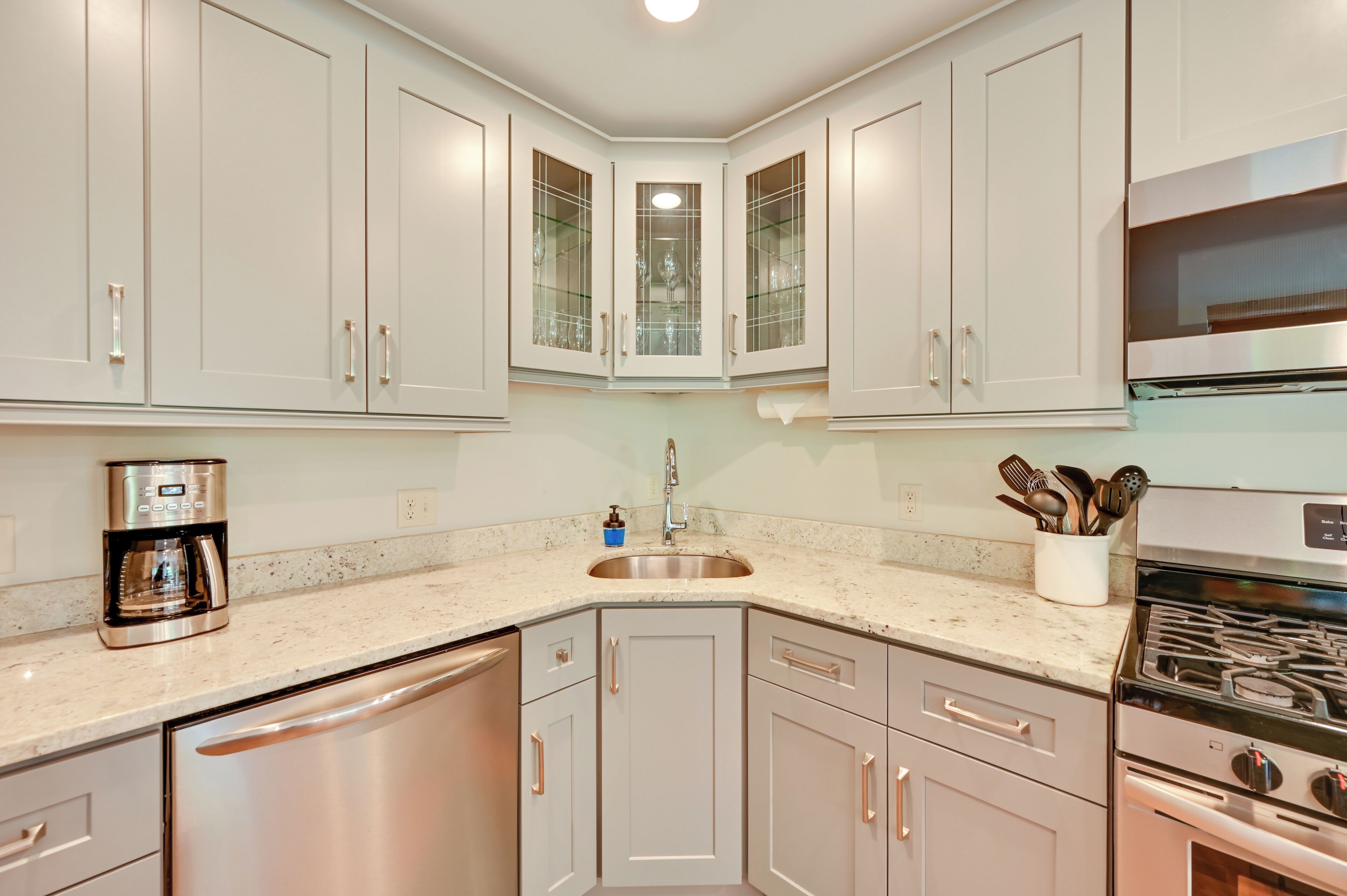 A modern kitchen with stainless steel appliances, white cabinetry, and a built-in oven.