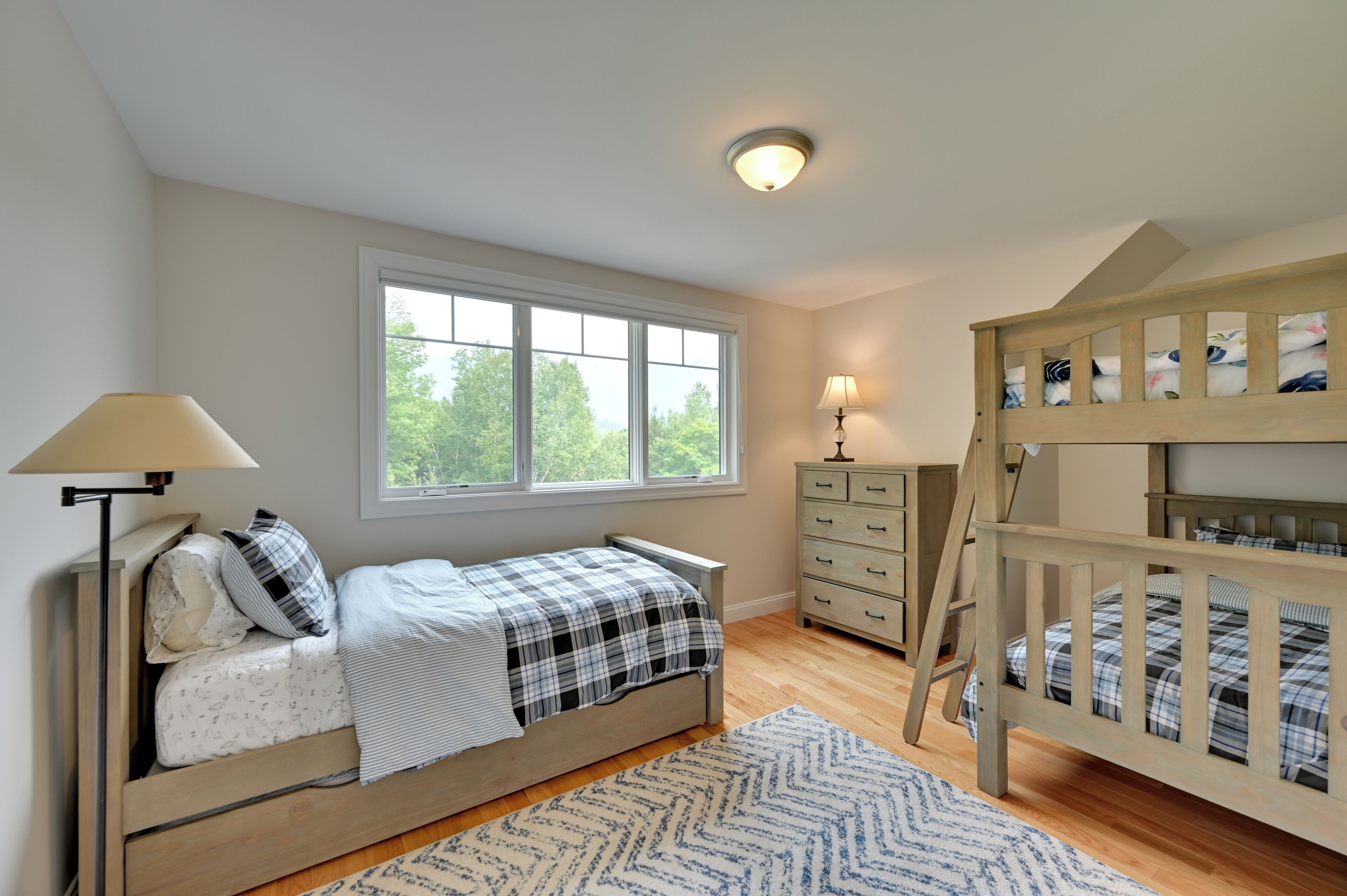 A bedroom with a bed, a dresser, a nightstand, a window, and a bunk bed.