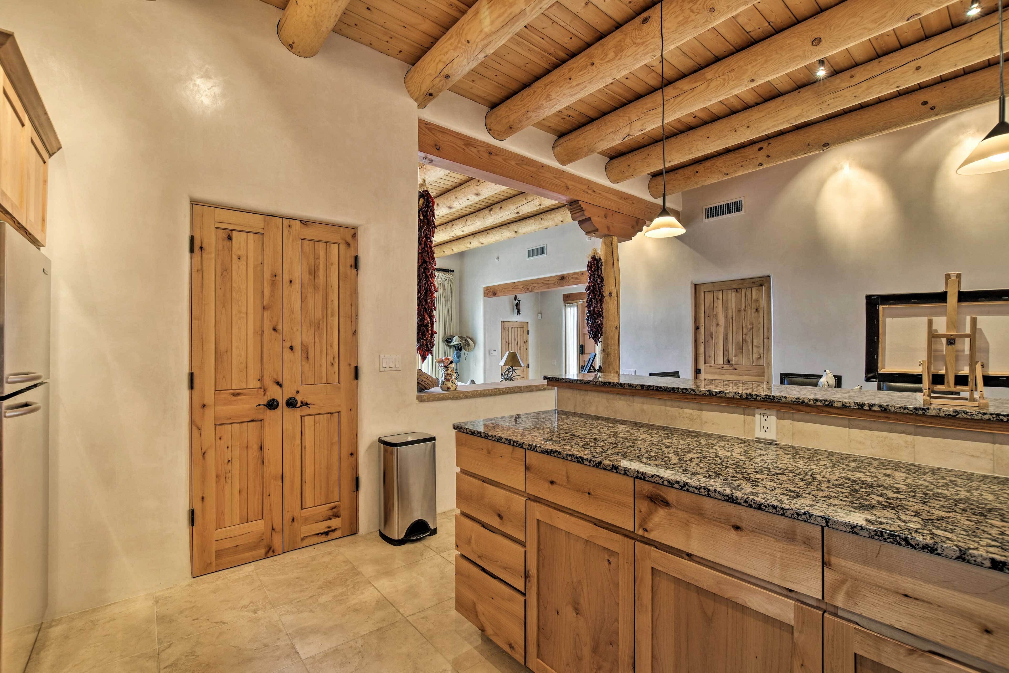 A kitchen with wooden cabinets, granite countertops, and a wooden ceiling.