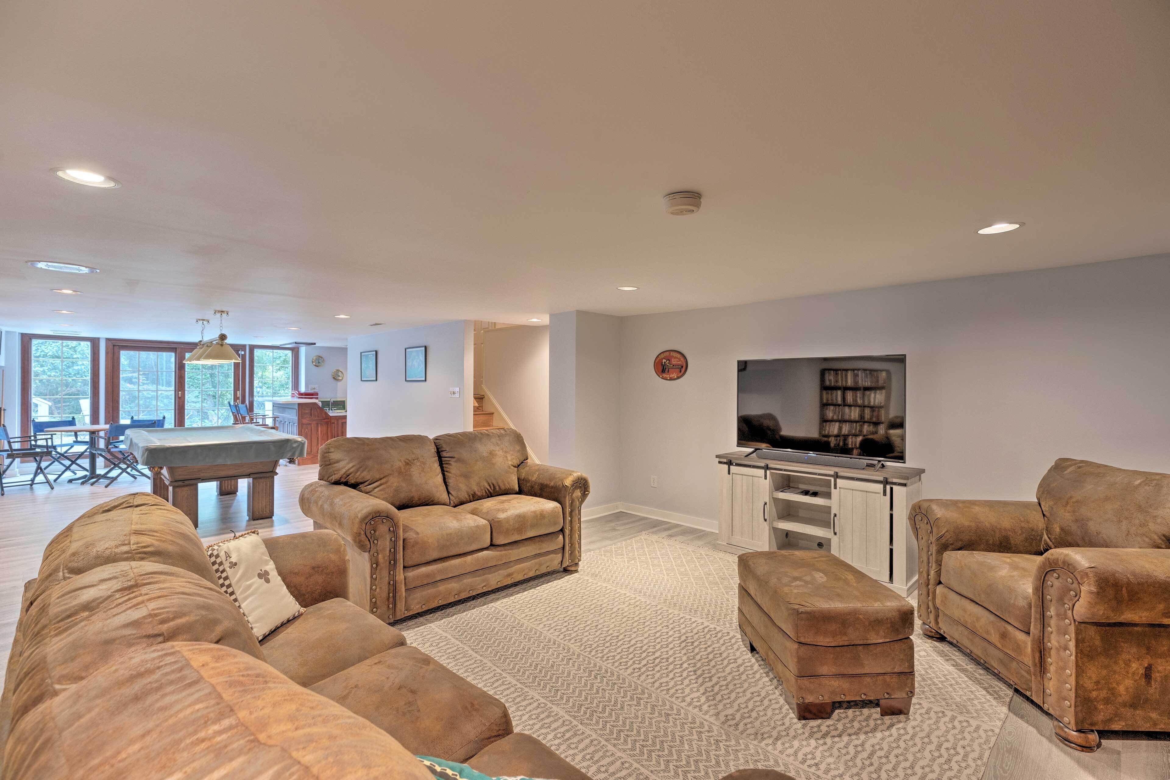 A spacious living room with a pool table, leather sofas, and a flat-screen TV.