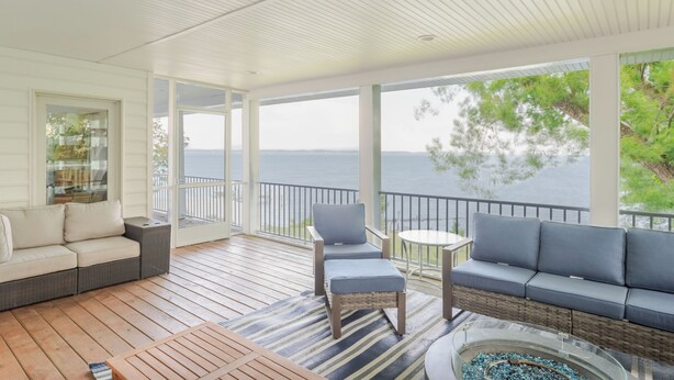 A covered outdoor area with a sofa, chairs, and a table. - Hot Tub + Private Beach: Waterfront Urbanna Escape (Urbanna)