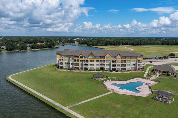 A large hotel with a swimming pool, a dock, and a well-maintained lawn. - Lakefront Paradise With Stunning Views! (Corsicana)