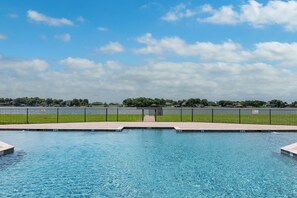 A swimming pool with a clear view of the sky and a distant fence line. - Lakefront Paradise With Stunning Views! (Corsicana)