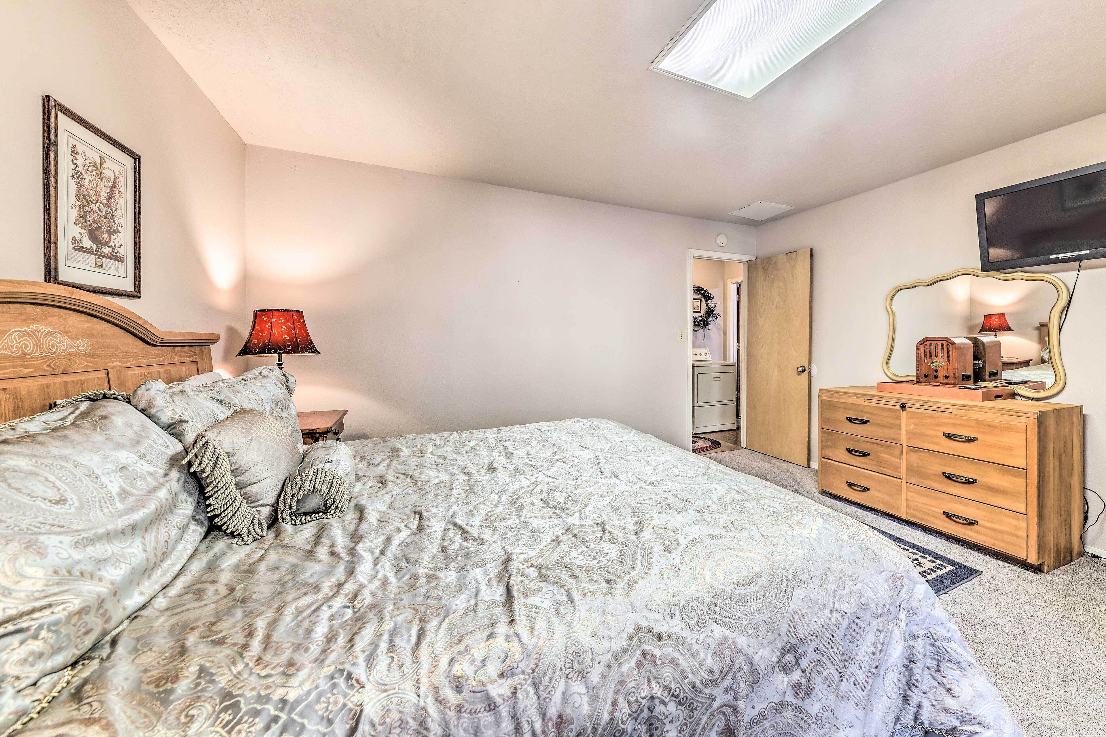 A bedroom with a bed, dresser, TV, and a framed picture on the wall.