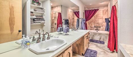 A modern bathroom with a large vanity, dual sinks, a shower area, and a built-in shelf with towels.