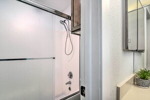 A modern bathroom with a glass shower enclosure, a wooden cabinet above the shower, and a potted plant on the countertop. - Brian Head Vacation Rental - Walk to Ski Lift (Brian Head)