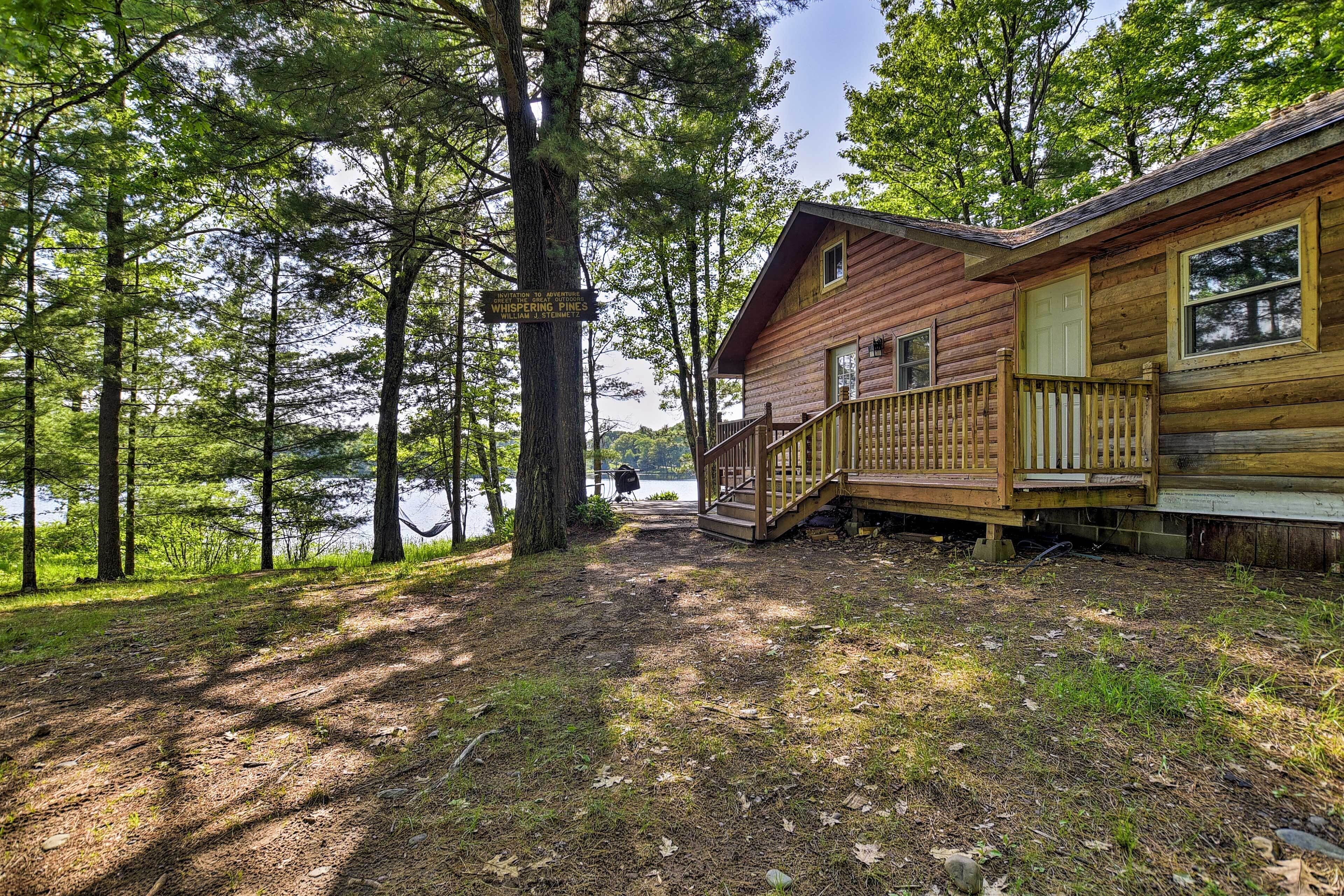 Une cabane en bois dotée d’une terrasse et d’une enseigne sur laquelle on peut lire : « Whispering Pines ».