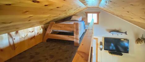 Un dormitorio acogedor en el ático, con una cama litera, un televisor y un pez montado en la pared.