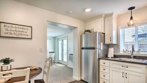 Una cocina moderna con armarios blancos, un refrigerador de acero inoxidable y una zona de comedor con mesa y sillas.