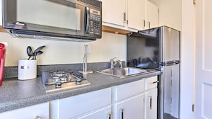 A modern kitchen with a microwave, gas stove, sink, and stainless steel refrigerator.