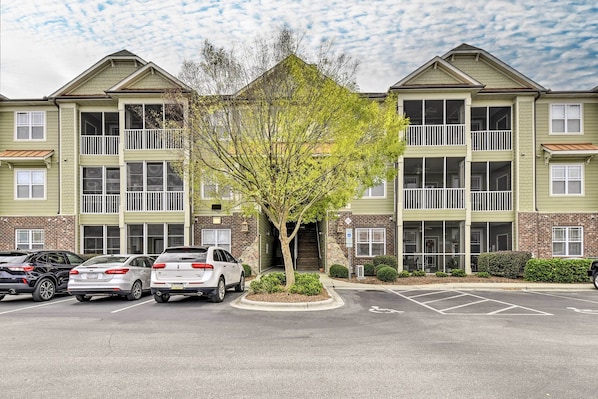 A multi-story building with a parking lot in front.