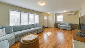 A spacious living room with a grey sofa, a wooden coffee table, and a small side table.