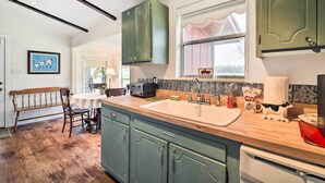 A kitchen with wooden cabinets, a sink, and a window. - On Scenic 60-acre Farm: Carmine Cottage w/ Porch (Carmine)