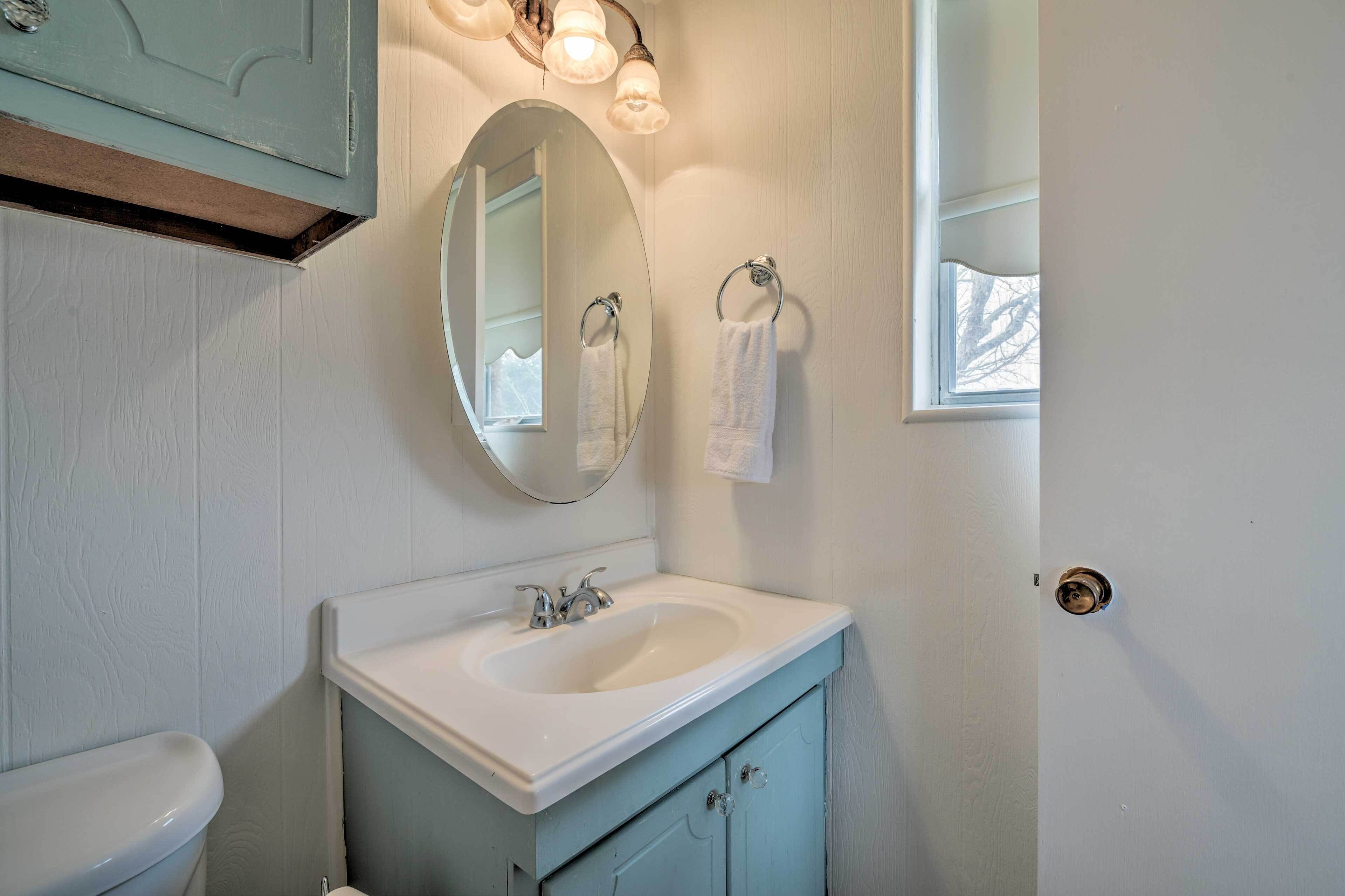 A bathroom with a white sink, a round mirror, and a towel rack.