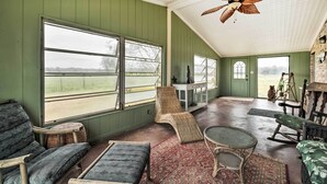 A room with large windows, a ceiling fan, wicker furniture, and a view of the outdoors. - On Scenic 60-acre Farm: Carmine Cottage w/ Porch (Carmine)